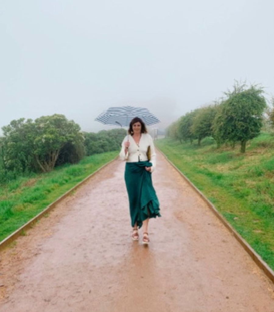 Valerie Jones walking down a misty country path under a striped umbrella